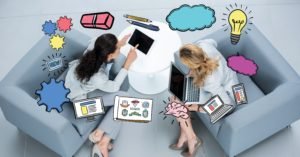 Various icons over businesswomen using laptops on couch